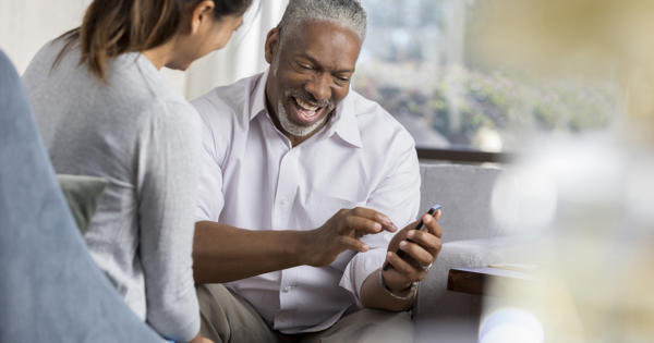 Older black man being shown how to use his phone