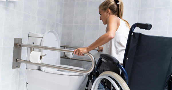 Women in wheelchair using grab rails - stock